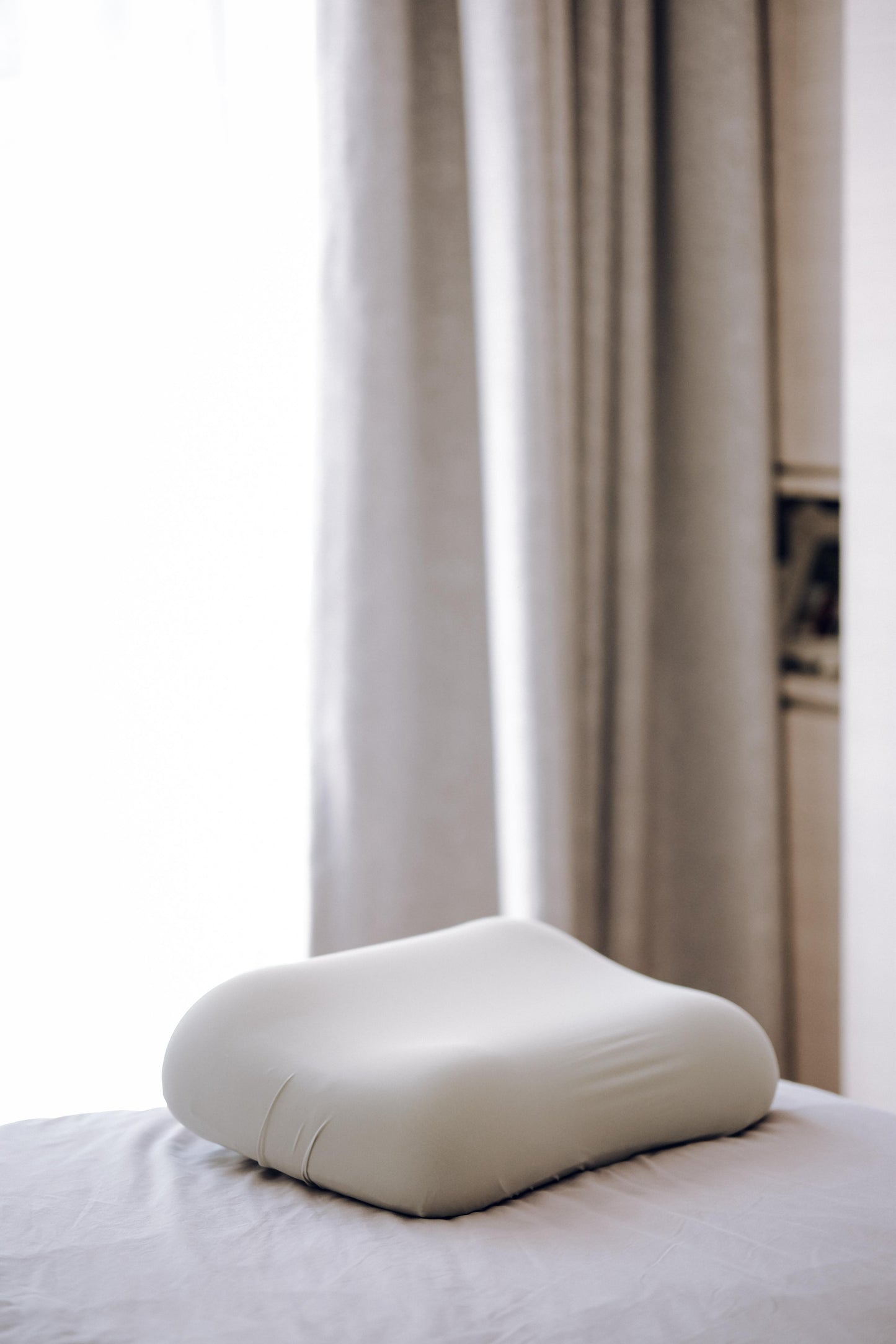 White pillow on a bed with curtains in the background